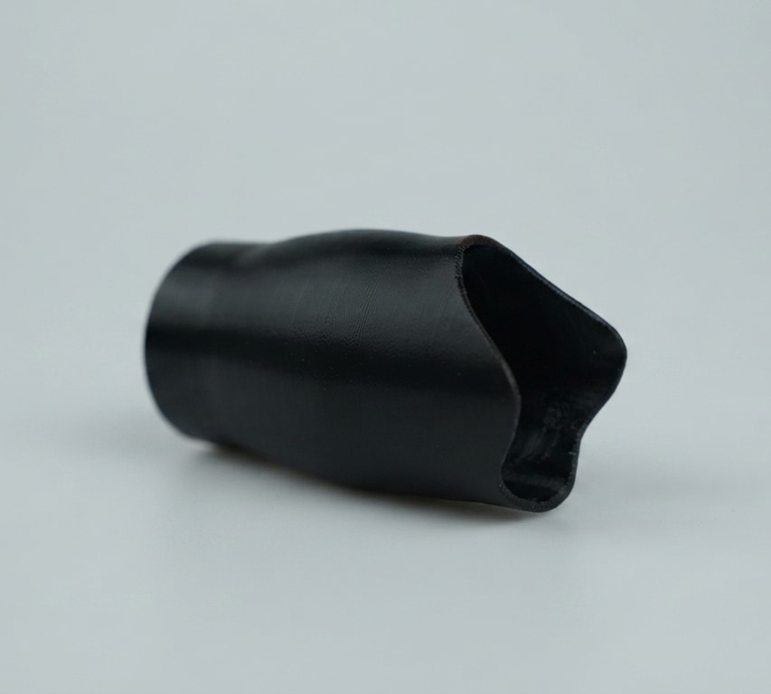 The printed socket, black, lying on a grey stage. Photograph.