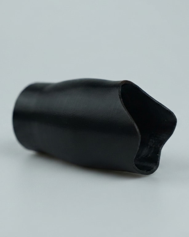 The printed socket, black, lying on a grey stage. Photograph.